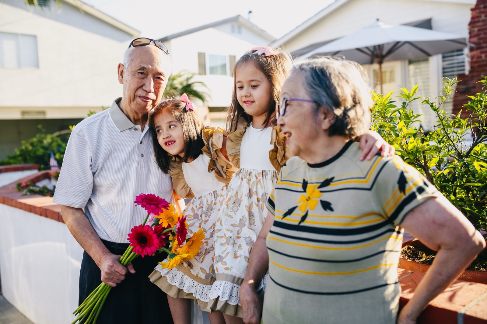 Grandparents laughing with their two granddaughters outside in the evening sun